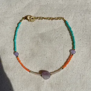 Detail of beaded bracelet with purple natural stones, turquoise seeds, and gold clasp