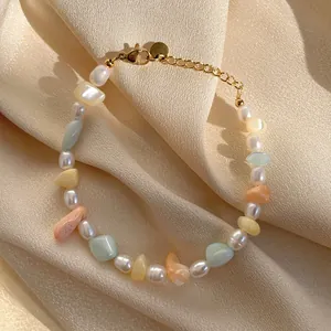 Détail d'un bracelet en perles d'eau douce avec pierres colorées sur de la soie