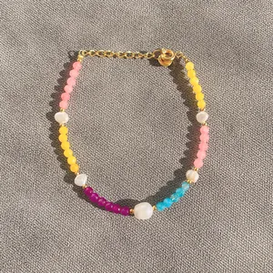 Vue détaillée du bracelet en perles colorées et perles d'eau douce sur lin gris texturé