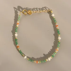 Détail macro du bracelet perlé avec pierres vertes, perles et fermoir mousqueton doré