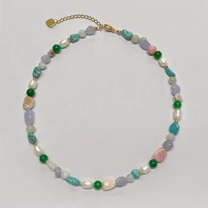 Colorful natural stone necklace with freshwater pearls and gold heart charm on white background
