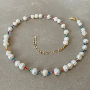 Detail of bohemian pearl necklace with colorful beads and golden lobster clasp