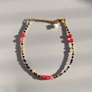 Detailed close-up of beaded bracelet with black stones, pink crystals and gold beads