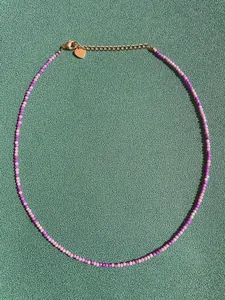 Macro detail of Bohemian beaded necklace with purple stones and gold heart charm