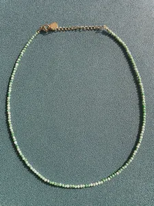 Detail of green beaded necklace with gold heart charm and adjustable lobster clasp closure