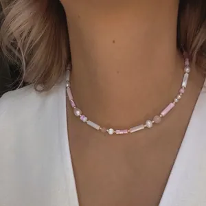 Detail of beaded heart necklace with baroque pearls and pink beads on a white linen shirt