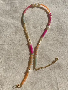Detail von bunten Perlen und Süßwasserperlen mit Goldverschluss auf Leinenstoff