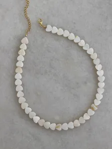 Detail of shell heart beaded necklace featuring white iridescent charms and gold clasp