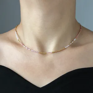 Pink natural stone beaded necklace with gold titanium steel accents on female neck