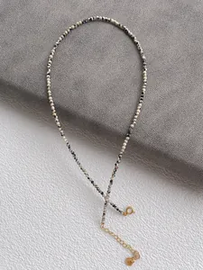 Close-up of minimalist natural spotted stone beaded necklace with golden lobster clasp
