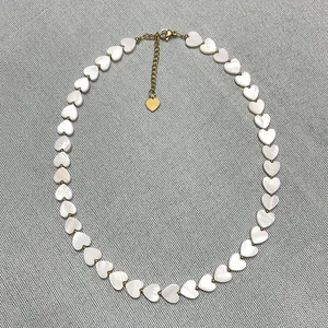 Detail showing heart-shaped shell beads and a 18k gold-plated heart pendant necklace