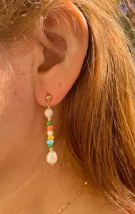 Détail de boucles d'oreilles pendantes avec perles colorées et perles d'eau douce baroques