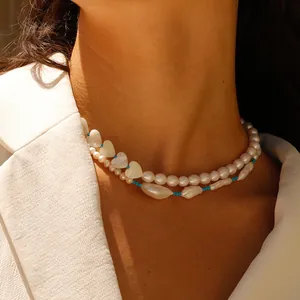 Detail of layered necklace with freshwater pearls, heart shell charm and blue beads