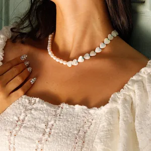 Close-up of shell heart beaded necklace with white pearls and blue accents worn on neck