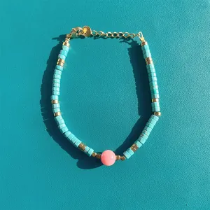 Bohemian style turquoise beaded bracelet with pink center bead and gold metal hardware
