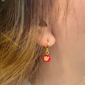 Pendientes de flores de cristal de colores con aros dorados usados por una modelo real