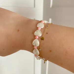 Detail of beaded shell heart bracelet set with gold finish heart pendant and zircon