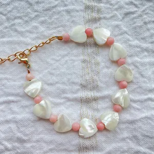 Detail shot of heart shell beads and pink pearls necklace with 18k gold lobster clasp