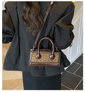 Detail of a leopard print handbag with leather patchwork and an elegant round top handle