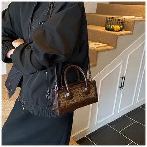 Detail of a brown leather crossbody bag with leopard print panel on a stair background