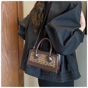 Detailed view of leopard print crossbody bag showing twin handles and shoulder strap