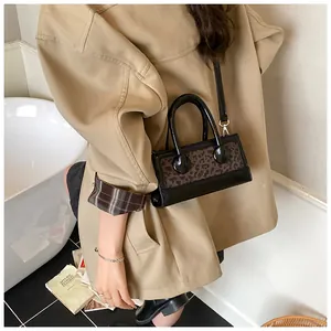 Fashionable leopard print handbag styled with khaki trench coat in a modern minimal setting