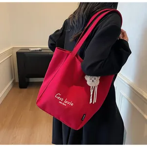 Détail du grand sac cabas en toile rouge avec broderie blanche et charm ours en peluche