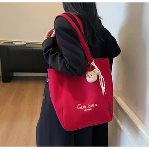 Détail du sac cabas en toile rouge avec lettrage artistique blanc et charm d'ours