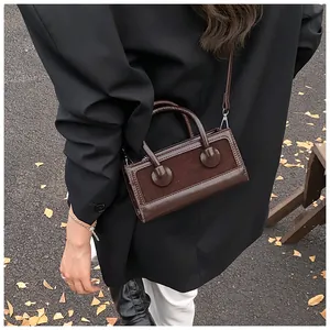 Detail of dark brown leather crossbody bag with leopard print and sleek gold buckles