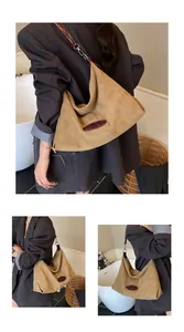 Detail view of khaki suede tote bag with brown leather logo patch and metal buckle