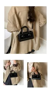 Detail view of the sleek black mini square bag with glossy finish and thin shoulder strap