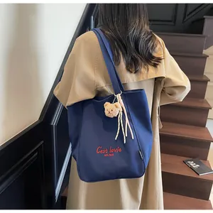 Détail du sac cabas en toile bleu foncé avec lettrage rouge et pendentif ourson