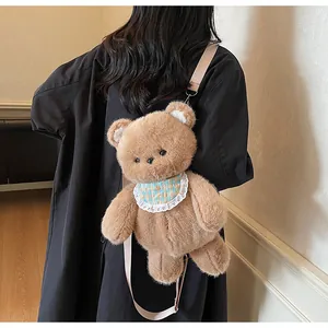 Detail of plush bear crossbody bag with plaid bib and pink strap on a dark coat