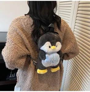 Close-up of cute plush penguin backpack with a soft grey fur and small blue fish accessory