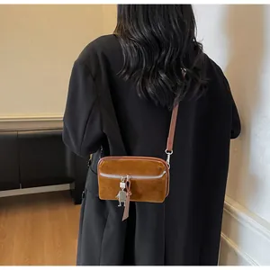 Detailed back view of a brown suede box bag featuring a robot charm and silver hardware