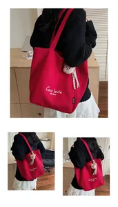 Détail du cabas en toile rouge avec imprimé C'est la vie et breloque ours en peluche