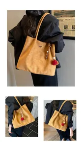 Detail of suede tote bag with decorative tassels and matte finish in mustard yellow