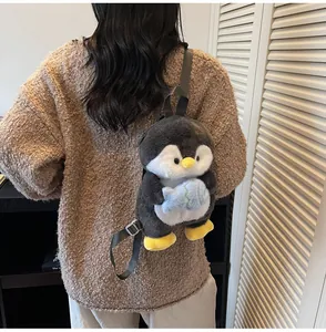 Detail view of a cute plush penguin backpack with small blue fish on model's back