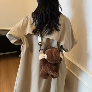 Cute brown plush bear crossbody bag with adjustable strap worn on a beige trench coat