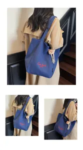 Détail du cabas en toile bleu foncé avec texte rouge et un pendentif ours en peluche