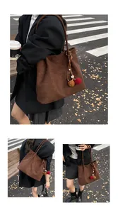 Close-up of minimalist dark brown suede tote bag with decorative tassels and gold logo detail