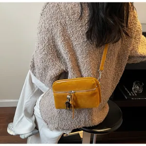 Detail of yellow suede mini crossbody bag featuring a cute silver robot metal charm
