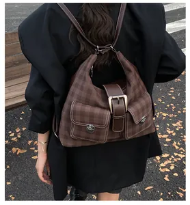 Detail of brown plaid backpack with dual front twist-lock pockets and autumn backdrop