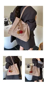Close-up of minimalist retro matte suede tote bag with ethnic style pompom charms