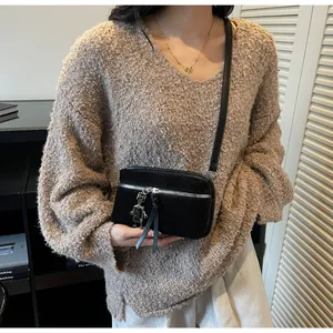 Détail du petit sac bandoulière noir aspect daim avec pendentif robot argenté tendance