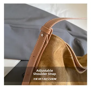 Detail showing adjustable brown suede strap with metal studs and white stitching