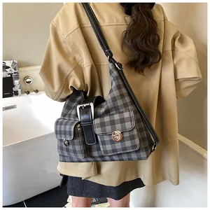 Model wearing a grey checkered canvas shoulder bag with metallic locks in a bright room