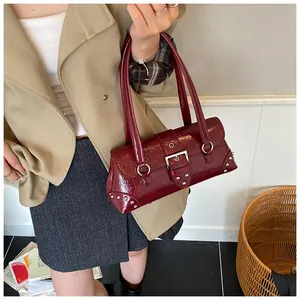 Close-up of a burgundy patent leather underarm bag with silver metal buckle detail