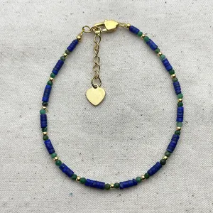 Handmade beaded bracelet with blue discs, green beads, and heart charm in gold finish