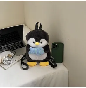 Close-up of plush penguin backpack with small blue fish detail on a white desk